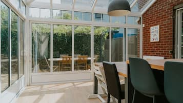 Un espace repas moderne avec une paroi vitrée, un mur en briques et une vue sur un jardin.