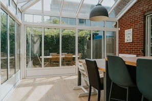 Een moderne eethoek met een glazen wand, een bakstenen muur en uitzicht op een tuin.
