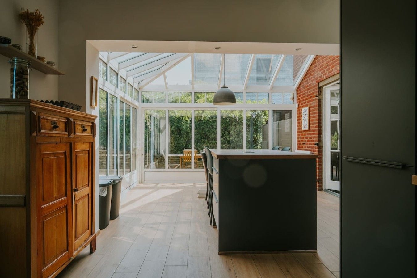 Une cuisine spacieuse dotée d’un grand îlot central, de meubles en bois et d’un patio vitré.