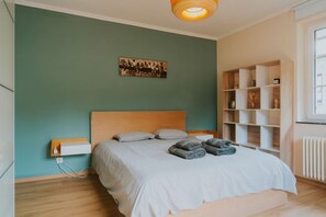 Ein Schlafzimmer mit Bett, Nachttisch, Regaleinheit und Wandbild.