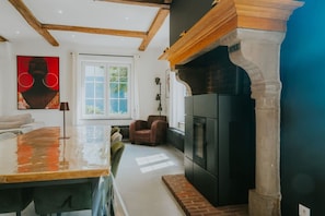 A modern kitchen with a black refrigerator, a wooden beam ceiling, and a large window.