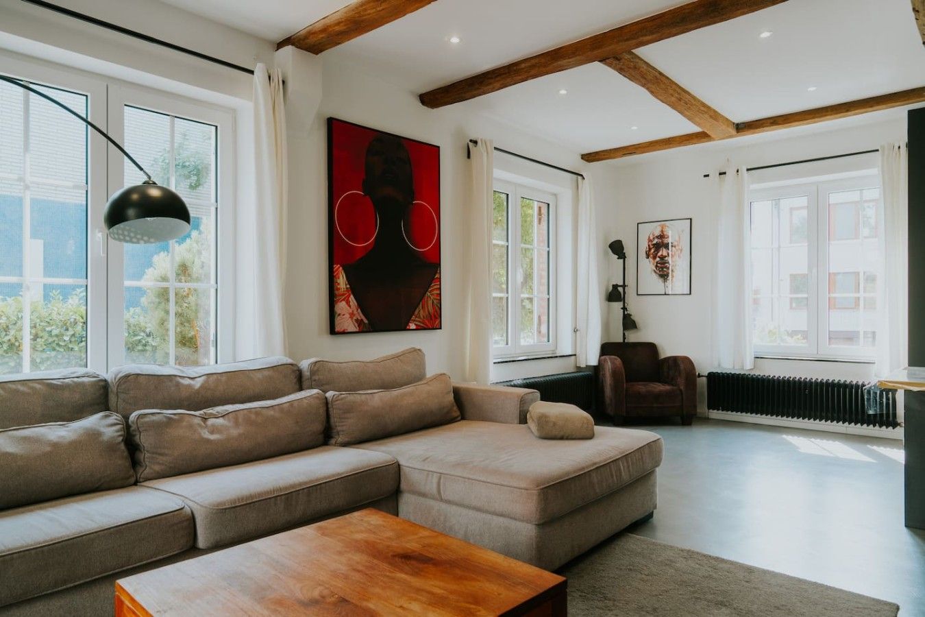 Ein modernes Wohnzimmer mit einem Ecksofa, einem Couchtisch aus Holz und Kunstwerken an den Wänden.