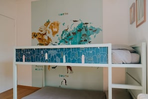 Een stapelbed met een wereldkaart muurschildering, waarop dieren en regio's afgebeeld zijn.