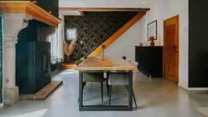Cozinha moderna com mesa de jantar de madeira, armários pretos e escada que leva a um andar superior.