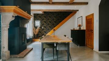 Une cuisine moderne avec une table à manger en bois, des meubles de rangement noirs et un escalier menant à un niveau supérieur.