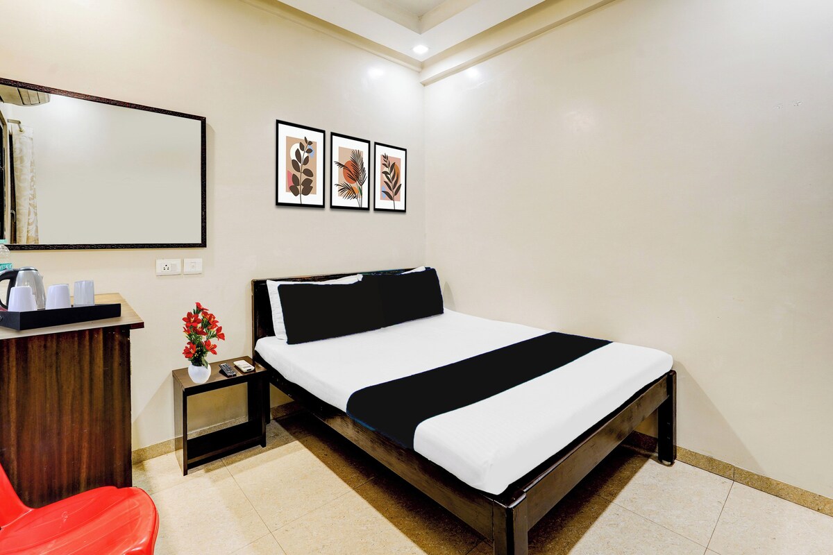 Habitación de hotel con cama, mesita de noche, un espejo y una pared con tres cuadros enmarcados.