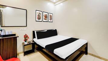 Habitación de hotel con cama, mesita de noche, un espejo y una pared con tres cuadros enmarcados.