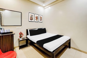 A hotel room with a bed, bedside table, a mirror, and a wall with three framed pictures. - Hotel O MA Chidambaram Stadium (Chennai)