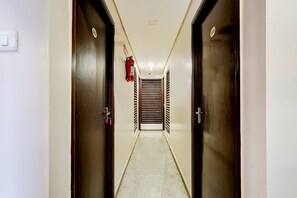 Un couloir avec deux portes, un extincteur et un mur muni d’une grille d’aération.