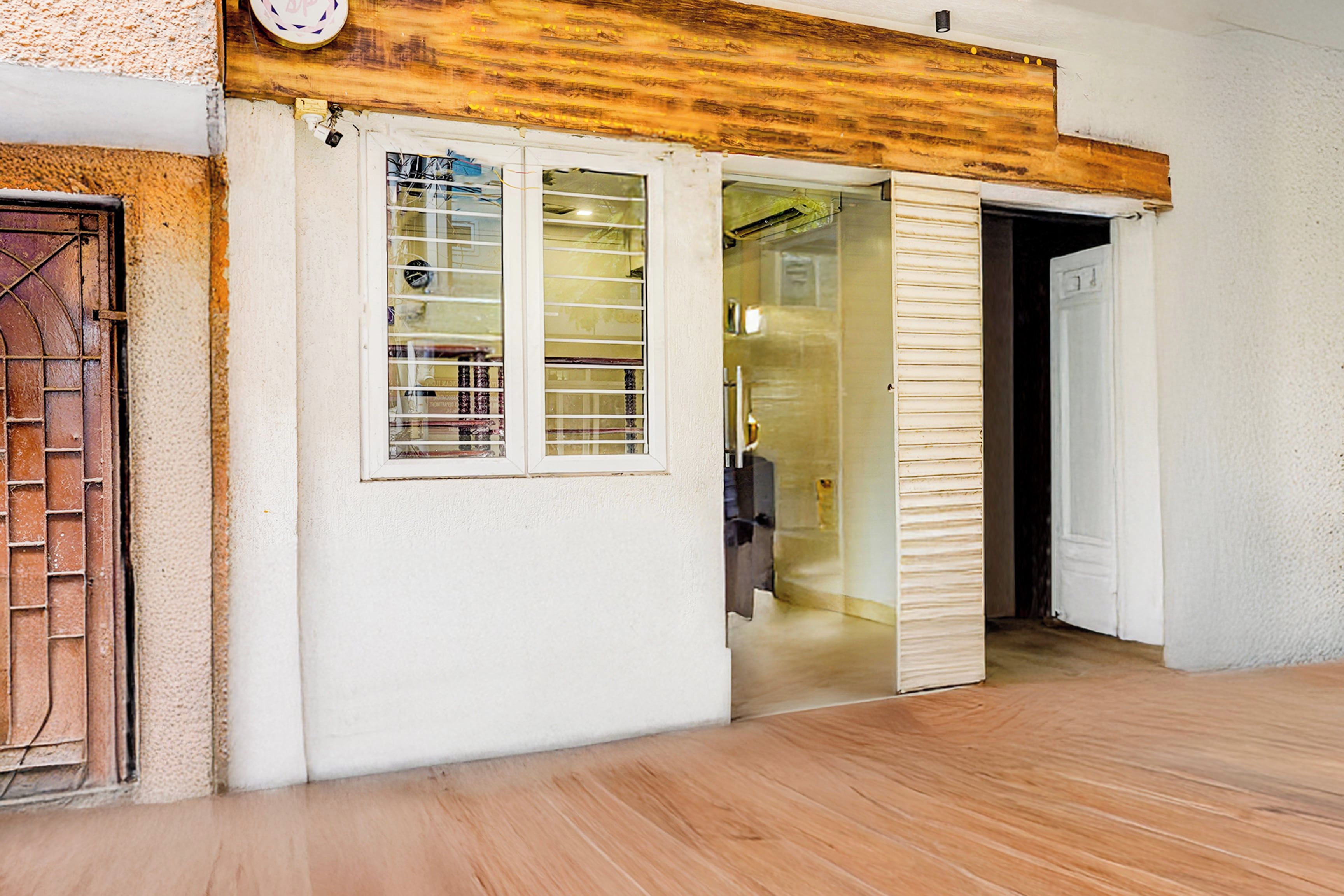 A room with a wooden ceiling, a white door, and a window with metal bars.