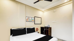 Una habitación de hotel con una cama grande, un aparador, un espejo y tres cuadros en la pared.