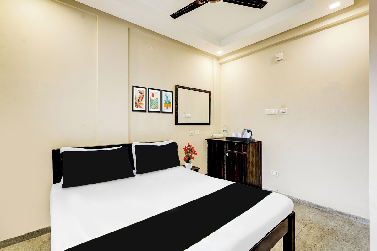 Une chambre d’hôtel avec un grand lit, une commode, un miroir et trois œuvres d’art encadrées accrochées au mur.