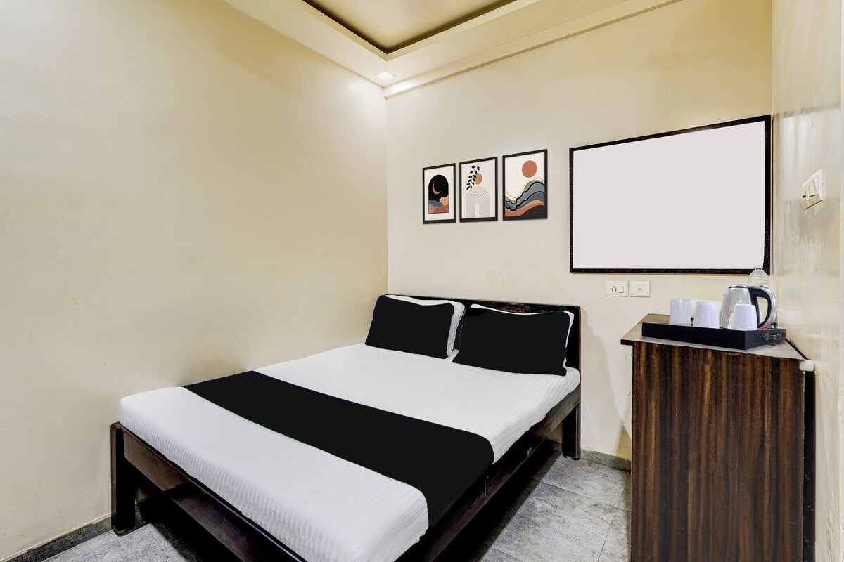 Una habitación de hotel con una cama, una mesita de noche con una tetera y tres cuadros en la pared.
