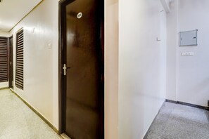 Un pasillo con una puerta cerrada marcada con el número 305, un interruptor de luz y un cuadro eléctrico de pared.