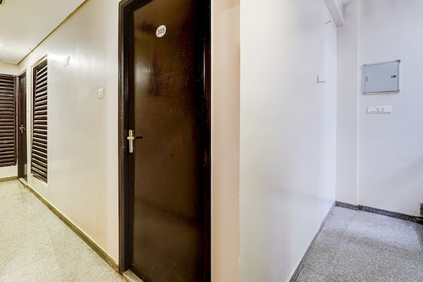 A hallway with a closed door marked with the number 305, a light switch, and a wall-mounted electrical box.
