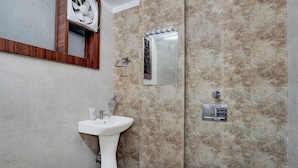Et badeværelse med et håndvask, toilet, et spejl og en håndklædestang.