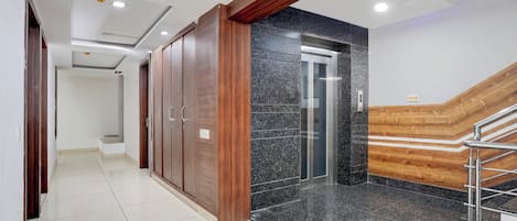 Un interior moderno con una escalera, un ascensor y un pasillo que lleva a otra habitación.