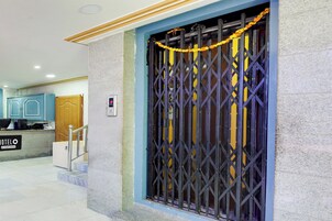 A hotel entrance with a metal gate, a reception desk, and a staircase leading to the interior.
