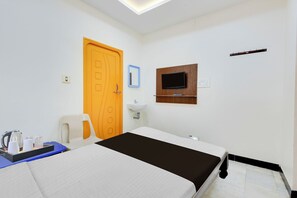 A hotel room with a bed, a desk with a kettle, a chair, a television, and a bathroom mirror. - Super Hotel O Guntur Railway Junction (Guntur)