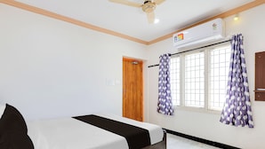 Ein Schlafzimmer mit einem Bett, Deckenventilator, Klimaanlage, einem Fenster mit Vorhängen und einer Tür.