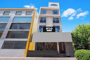 Entrada de hotel con diseño moderno, que presenta un letrero llamativo y una escalera que conduce a la entrada.