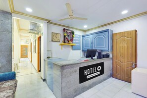 A hotel reception desk with a clock, a computer, and a sign indicating it's a company-serviced hotel. - Super Hotel O Guntur Railway Junction (Guntur)