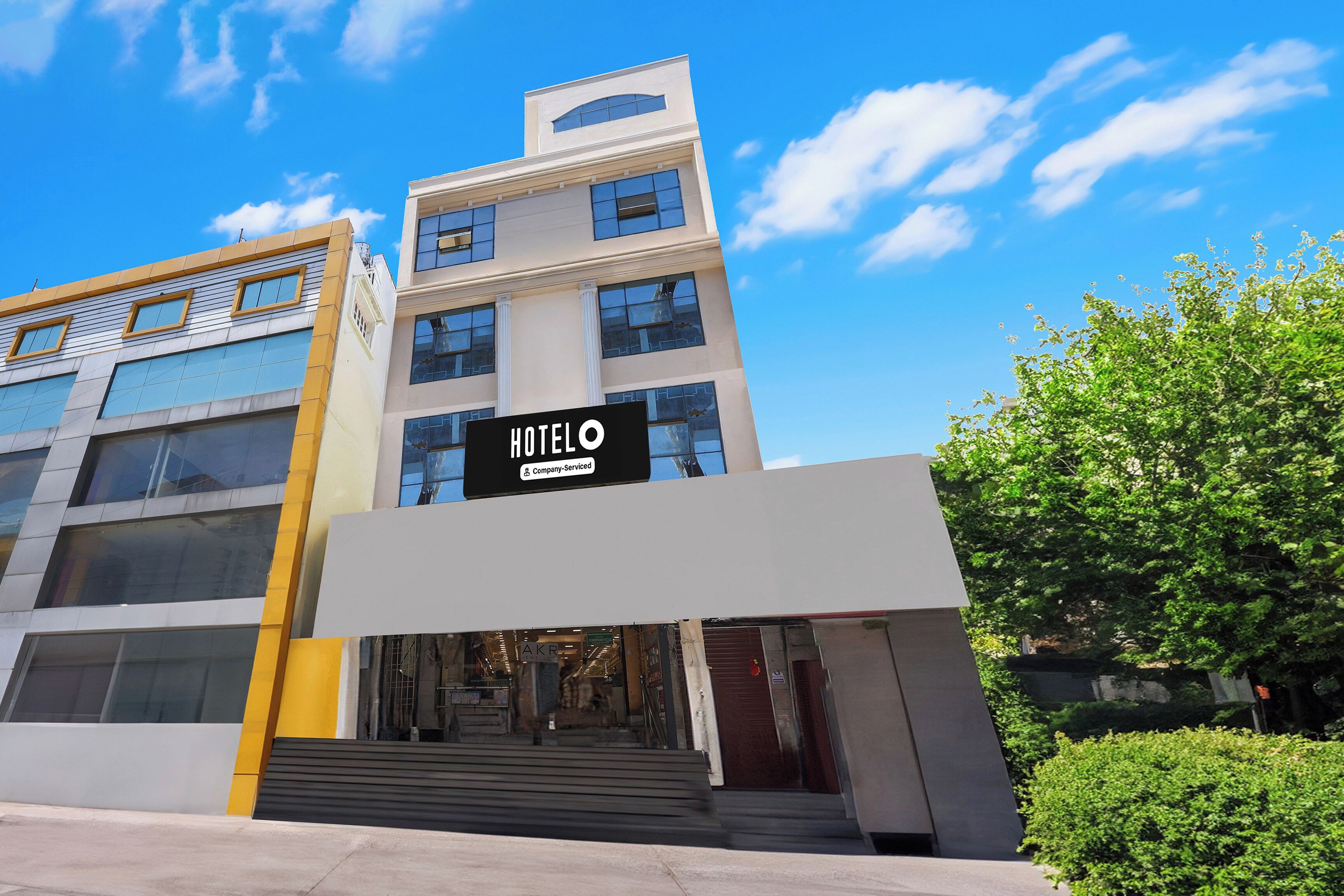 A modern hotel building with a prominent sign reading 'HOTEL O Company Serviced'.