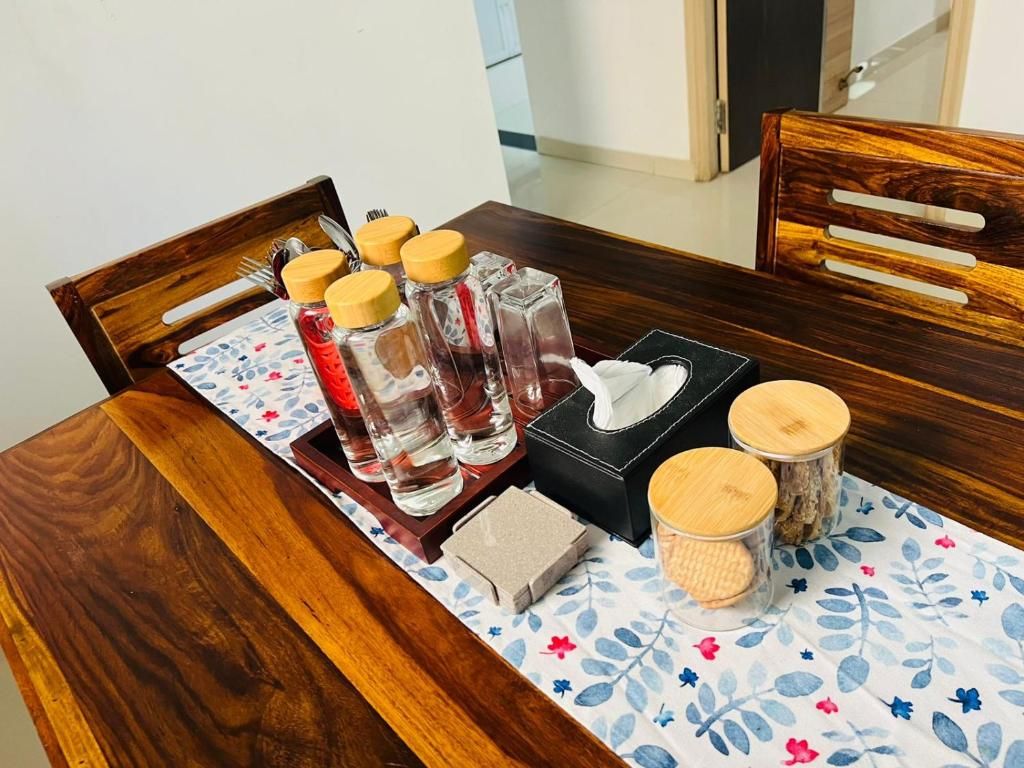 A wooden dining table with a floral tablecloth, a tray with condiments, a tissue box, and a small container.