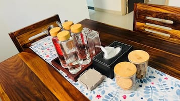 A wooden dining table with a floral tablecloth, a tray with condiments, a tissue box, and a small container.