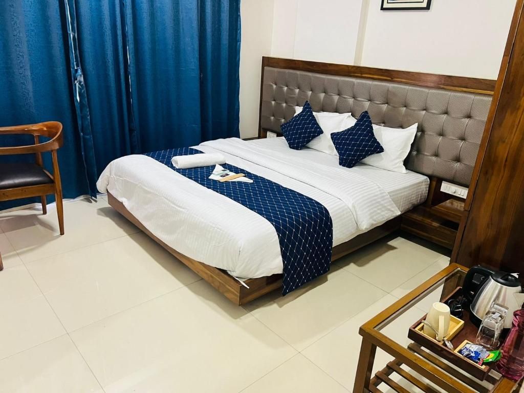 A neatly made bed with a wooden frame, a headboard, and a blue patterned bedspread.
