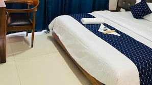 Ein Hotelzimmer mit einem Bett, einem Sessel, einem Schreibtisch und einem Fenster mit Vorhängen.
