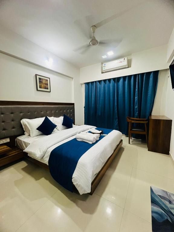 A hotel room with a bed, a ceiling fan, an air conditioning unit, and a blue curtain.