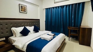 Ein Hotelzimmer mit einem Bett, einem Deckenventilator, einer Klimaanlage und einem blauen Vorhang.
