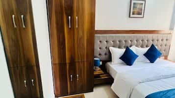 A hotel room with a bed, wooden wardrobe, bedside table, and a tray with items.