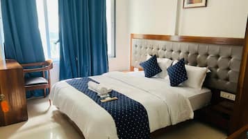 Quarto de hotel com cama, escrivaninha e cadeira.