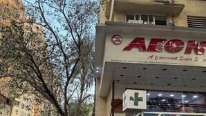 Un edificio con un letrero que dice 'AEON' y una farmacia en la planta baja.