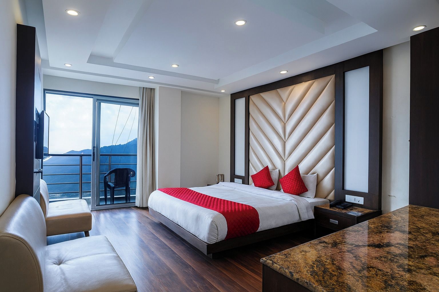 Una habitación de hotel moderna con una cama grande, un área de descanso con vistas y un balcón.