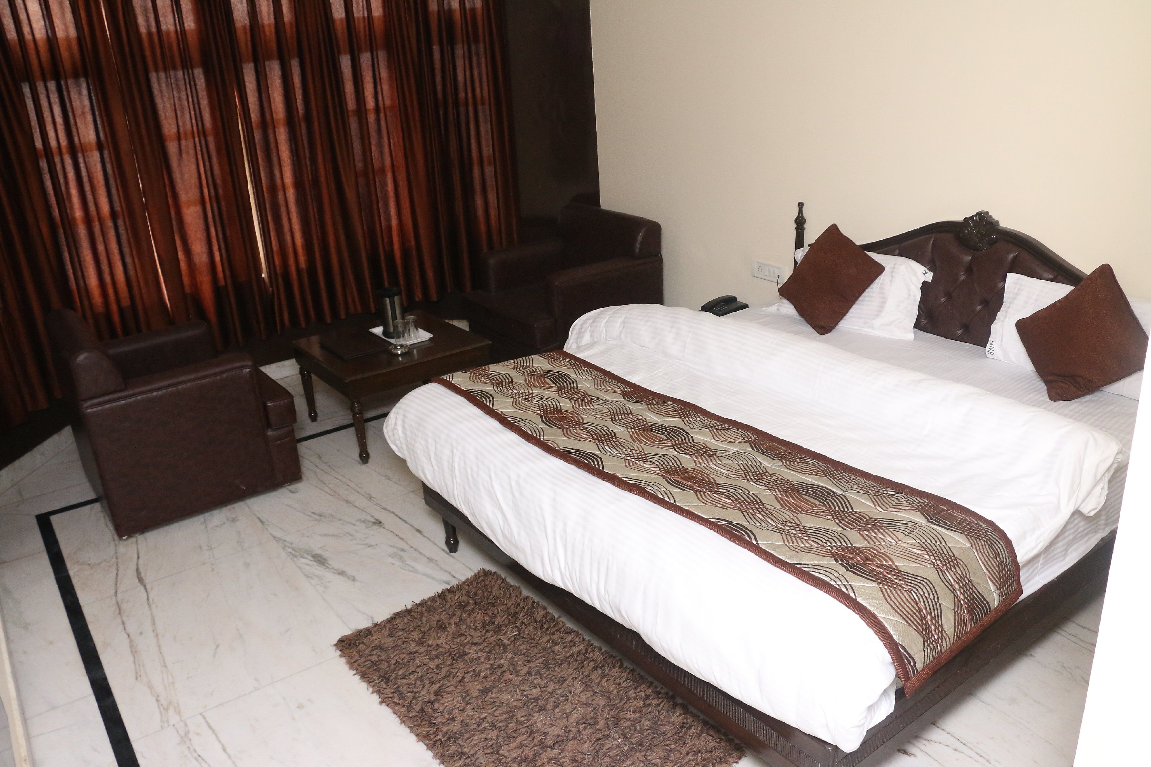 A hotel room with a bed, a desk, a chair, and a sofa.