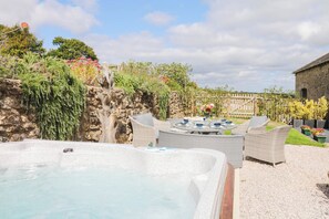 A hot tub with wicker furniture and a stone wall. - Halshanger Barn (Newton Abbot)