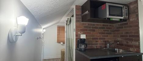 A compact kitchen with a microwave, coffee maker, and dishwasher.