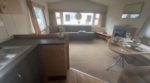 A compact living space with a kitchenette, a sofa, a dining table set, and a fireplace.