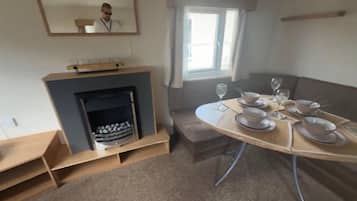 A dining area with a table set for four, a fireplace, and a window with curtains.