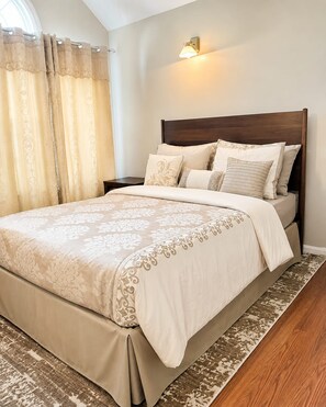 A neatly made bed with a patterned bedspread, a headboard, and multiple pillows.