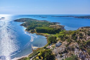 Eine Küstenlandschaft mit freiem Blick auf das Meer, felsigem Gelände und einem Gebäude mit geneigtem Dach.