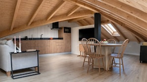 A loft-style room with a kitchen, dining area, and a cozy seating space.