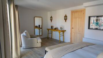 Una habitación de hotel con una cama, una silla, un escritorio, un espejo y una puerta.