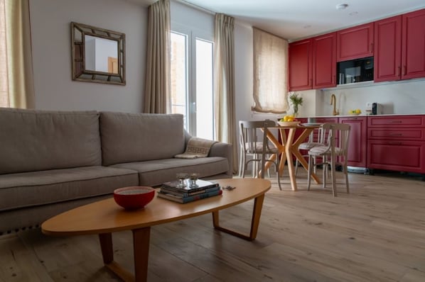 A living room with a sofa, a coffee table, and a dining area with chairs and a table.