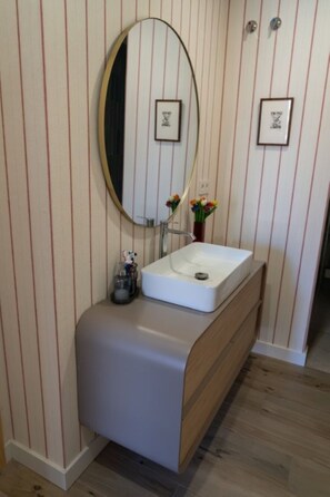 A bathroom with a white sink, a mirror, and striped wallpaper.