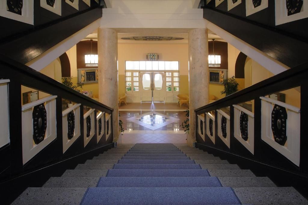 Una imponente escalera con un espacio abierto en el centro, flanqueada por columnas y detalles decorativos.