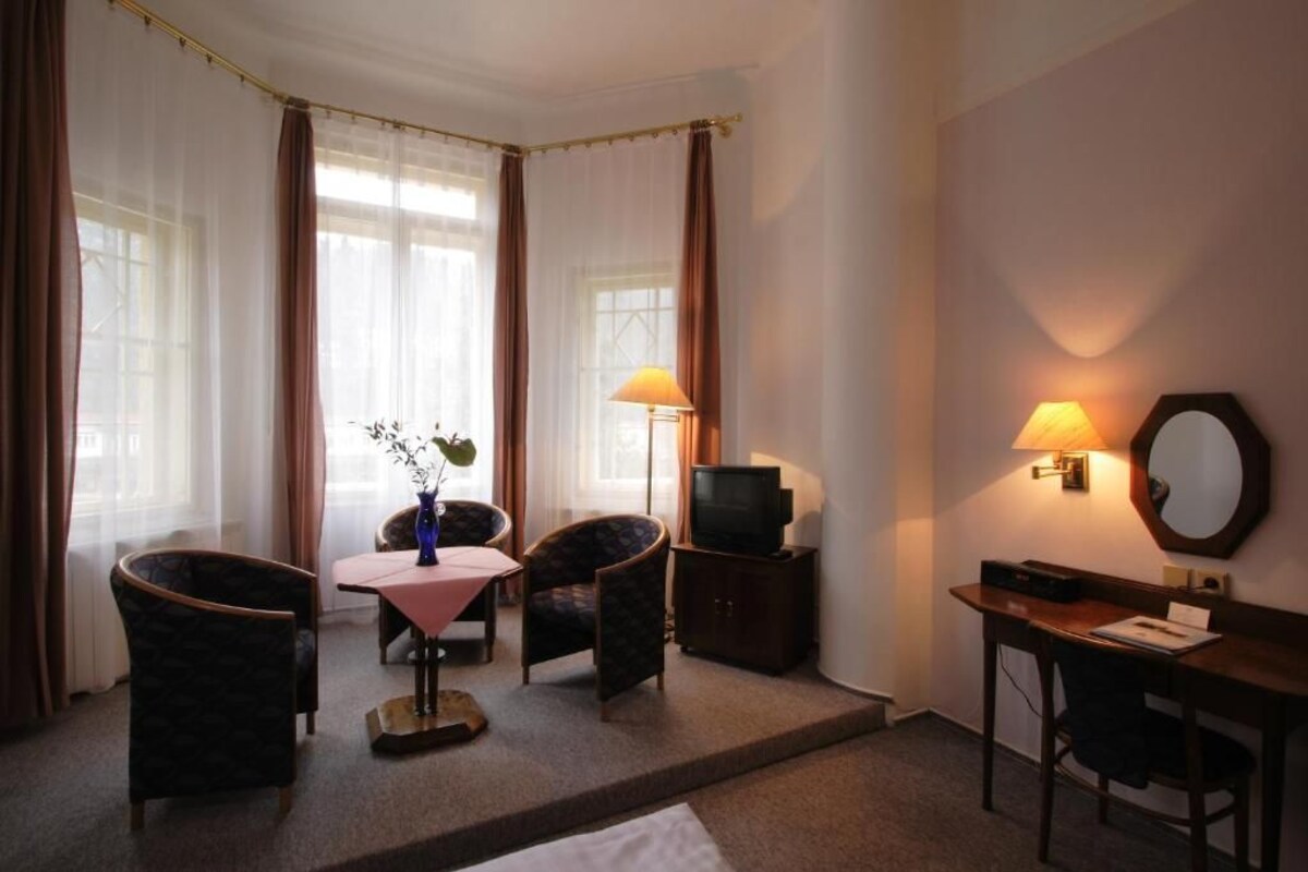 Una habitación de hotel con cama, escritorio, silla, televisión y lámpara.
